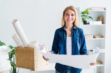 smiling-blond-woman-designer-with-big-unrolled-paper-sheet